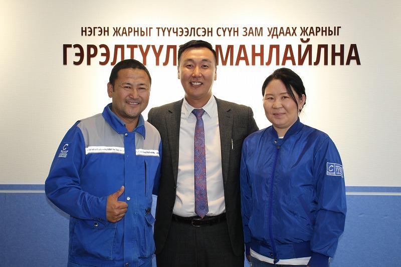 聴覚障害があるビャンブドルジさん（左）と、妻のツァサンチメグさん（右）と共に笑顔を見せる行政人事部長のアリウンボルドさん（中央）