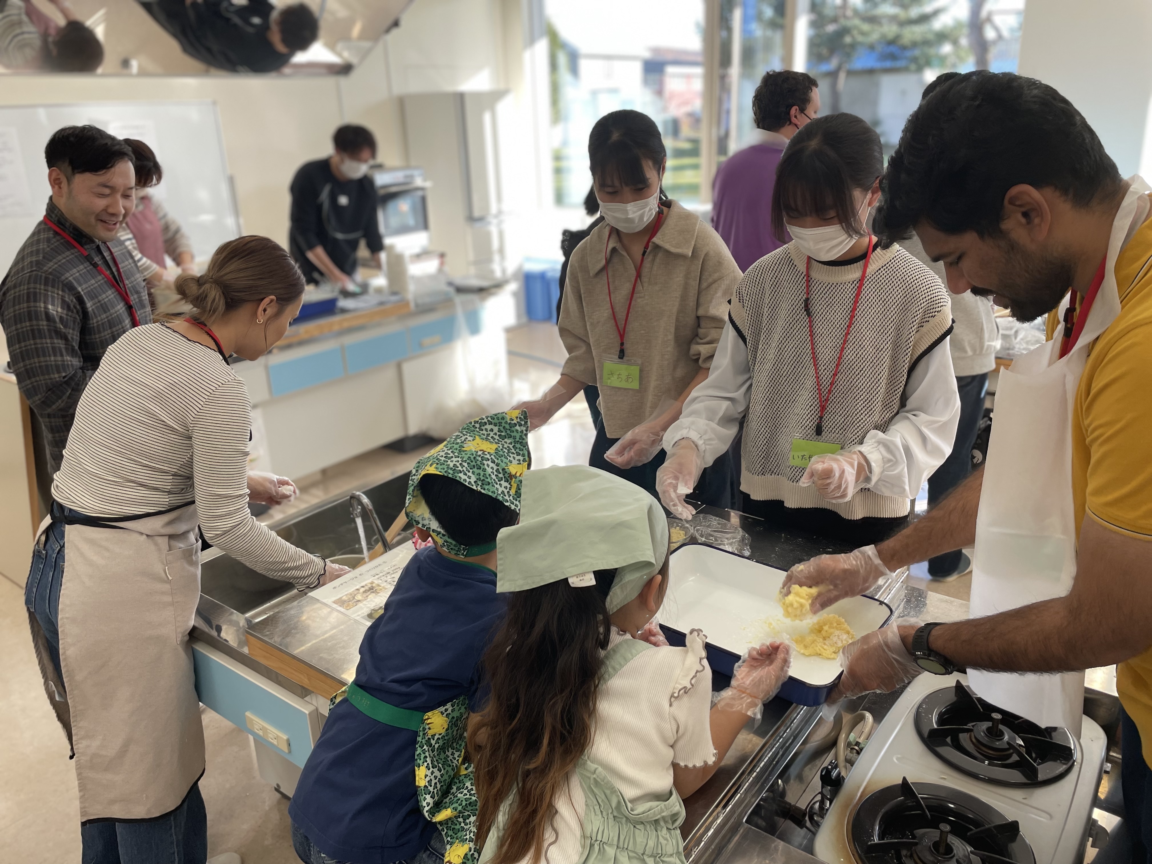 実習室では北見市のきたみ国際ふれあいカフェが実施され、日本人と外国人合わせて60名が交流しながらブラジルのパン“ポンデケージョ”を作りました
