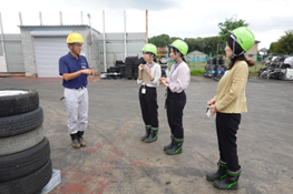 堤さんがJICAの職員とインターン生（小俣・宮内）に車の解体について説明する様子