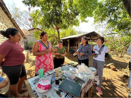 女性向けの集落でのワークショップの様子。調理実習をしながらそれぞれの生活改善行動について披露している。）