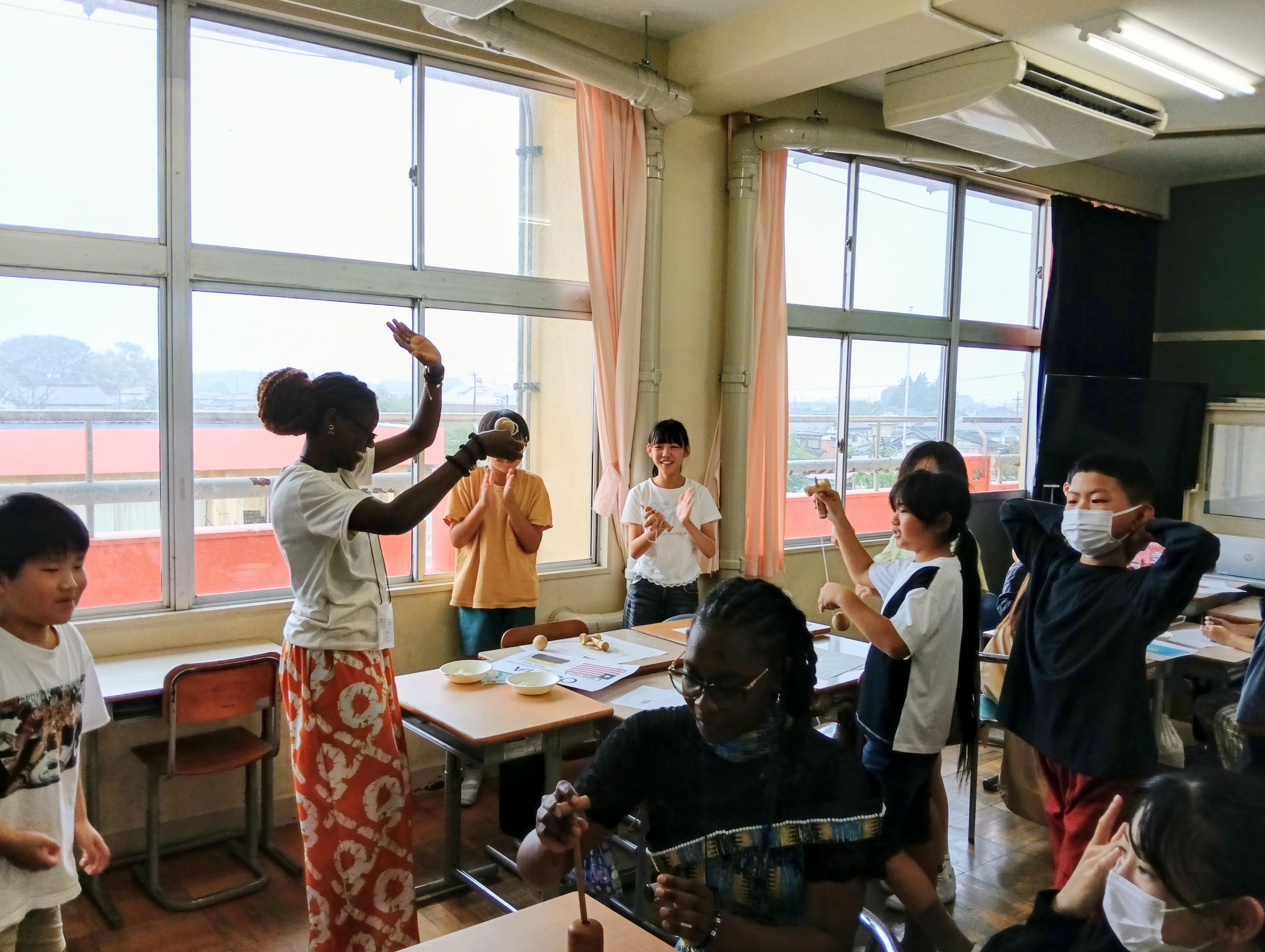 （写真④）：けん玉、だるま落としに挑戦する研修員①