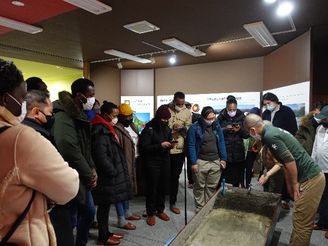 JICA scholars at the Tokachi Shikaoi Geopark Visitor Center, looking at a model and listening to the explanation on the Tokachi plains’ formation processes.