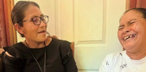 The woman (right), who used to be an illiterate, became able to write three letters of her name, encouraged by the community extended worker (left)