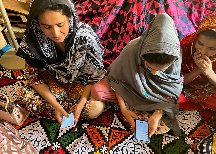Women learning to operate a smartphone as part of digital marketing training.