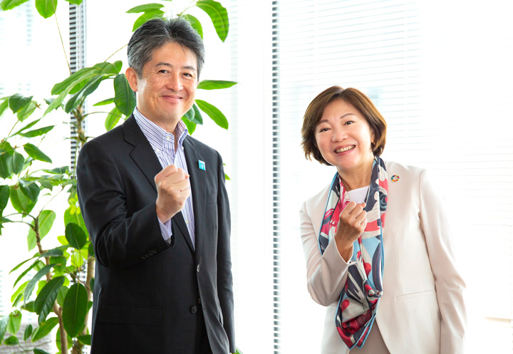 Professor Oki and JICA's Miyazaki clenching their fists in a gesture of determination.
