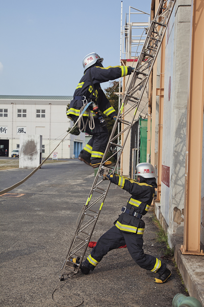 Des stagiaires utilisent une échelle d’escalade pour entrer dans un bâtiment en « feu ».