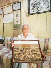 第一陣入植者（11家族81人）の神戸港での集合写真を手にする関淳子さん。このうち、今もラ・コルメナで生活している人は、関さんを含めて2人しかいないという