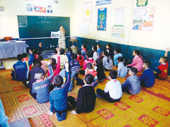 モデル地区の小学校で行われた環境教育の授業。子どもたちは、プロジェクトが製作した絵本などでごみについて学んだ
