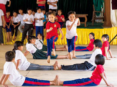 【小学3年生：脚飛び越えレース】仲間が脚を伸ばして作った障害物を2人1組のペアで飛び越えていく。ゴールしたペアは新たな障害物を作り、障害物だったペアが新たな走者となり、全員が一巡するまでのスピードを競う。どっちのチームが速いかな？