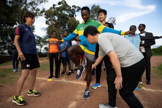 ルワンダ若手陸上選手（中央）に新たな練習準備方法を指導する飯塚翔太選手（選手の後ろ）と豊田裕浩コーチ（右）、サポートする林理紗陸上競技隊員（左）