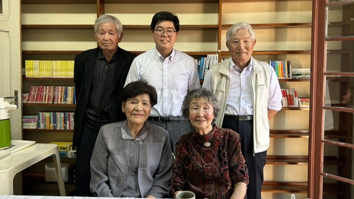 写真：2025年9月、サンパウロにて、工業移住者である金谷さん夫妻（左）、大矢さんご夫妻（右）、JICA緒方研究所の田中秀一研究員（後列中央）。金谷義弘さんは生産管理のエキスパートとして日系電機メーカーで、大矢進貞さんは金型設計工として外資系自動車メーカーで活躍した。金谷治美さん、大矢紀子さんは、「ブラジルは自由に暮らせてよかった」と語った。田中研究員による金谷さん・大矢さんご夫妻へのインタビュー動画を近く公開予定