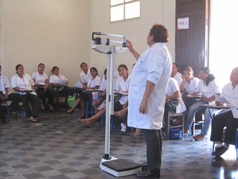 体重測定：看護学演習の時間に看護教員が体重及び身長の測定方法を指導している様子。日本から供与された体重・身長計（一体型）を使用している。