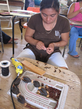 地元の自然素材を利用して作品を作る女性達。種子を使ってネックレスを作っています。