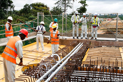 橋梁建設現場で進捗状況をチェックする日本人技術者と現地技術者。現地技術者の育成も大切な目的のひとつ。（写真提供　飯塚明夫）