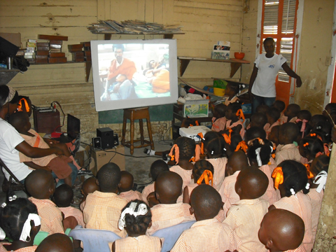 緊急リハビリ事業（衛生教育）：学校の教室で、衛生教育に関する映画に見入る子どもたち。地震後にコレラが蔓延したハイチでは衛生教育への関心が高く、学校で学んだ子どもたちから家庭や社会に衛生観念が普及しているところである。