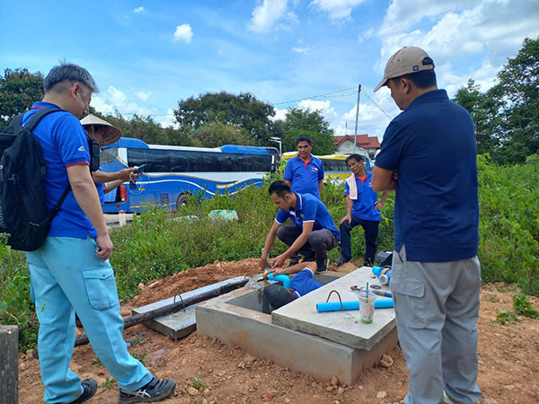 デンサワン給水区域内に設置された排水施設で排水方法を指導する石川専門家（左）