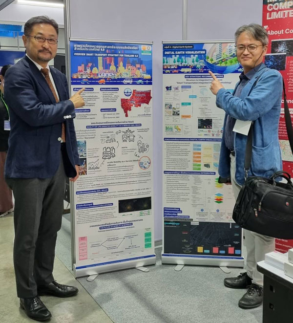 プロジェクト紹介ポスターの前に立つJICAタイ事務所・鈴木所長（左）と安藤業務調整員（右）