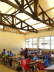 （応急対策工事後）：教室は仮設の防水シートで覆われ、日差しや雨水の流入が遮断され、快適な学習環境の中で授業を受けられるようになりました。本小学校では教室棟4棟で仮設屋根シートが設置されました。
