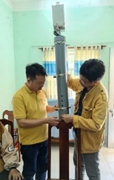 水田に設置する予定の水位計について説明する、モデルNo. 1リーダーのニアさん（左）とモデルNo. 11リーダーのタイさんの画像