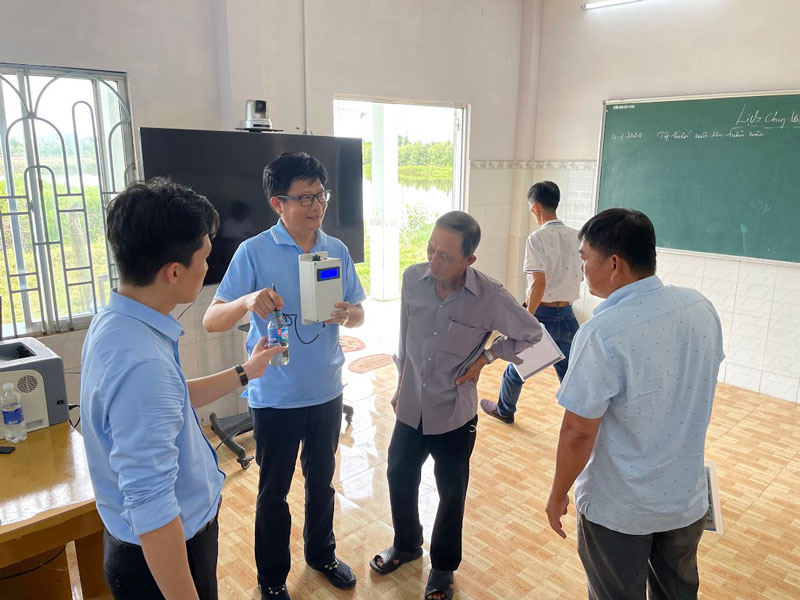 水質計測装置の実物を見せながら環境モニタリング技術について説明するThái先生（左から２人目）。