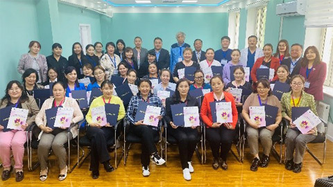 修了証と看護ToT研修の冊子を持って参加者らと共に
