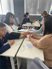 配られたスパゲッティ・紐・テープなどを使って試行錯誤する研修生の様子