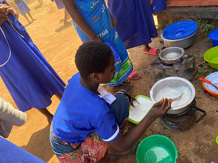Students making nsima in a cooking class, with careful instructions on how to make them.