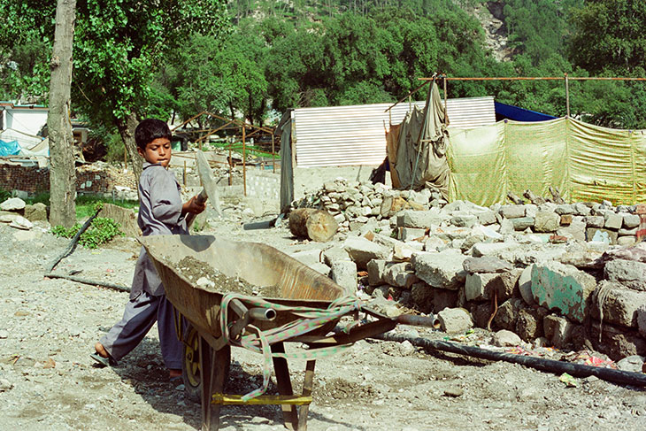 地震で倒壊した自宅の瓦礫を撤去する少年