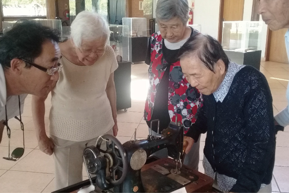 移民歴史資料館で古い道具を懐かしそうに見つめるお年寄りたち