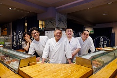 あたぼう鮨の店内での藤川さん（中央）と板前、おかみ。
開店と同時にカウンター18席、テーブル16席が予約の客で埋まっていくほど人気の店