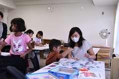 乗り物の写真と説明文が載ったプレートで遊ぶ少年とメンバーの松原さん