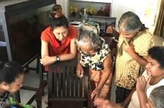 数字を書いた紙の上に、同じ数字のペットボトルのふたを探して置くゲームをする、施設入居者と岡澤さん