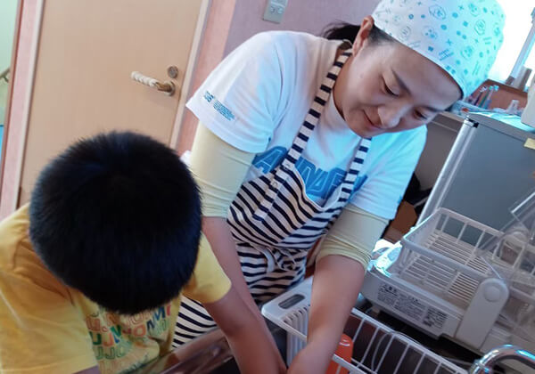子どもと米研ぎをする吉岡さん。様々な体験を一緒に行うことで、子どもが自信を持って、楽しみながら成長できるよう、応援する。